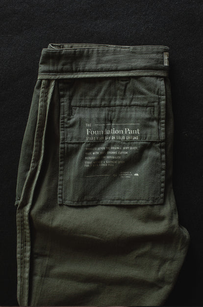 A pair of Foundation Pants folded on a black background, showing the back pocket.