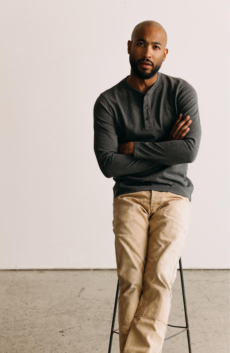 fit model sitting on a stool wearing The Heavy Bag Henley in Heather Grey