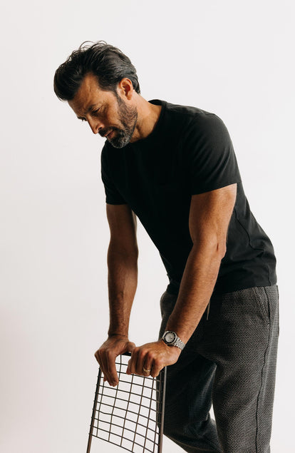 fit model leaning against a chair wearing The Heavy Bag Tee in Black