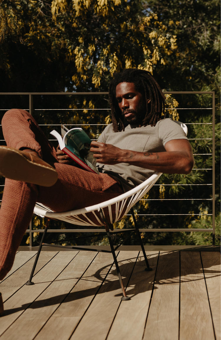 fit model sitting in a chair wearing The Heavy Bag Tee In Smoked Olive