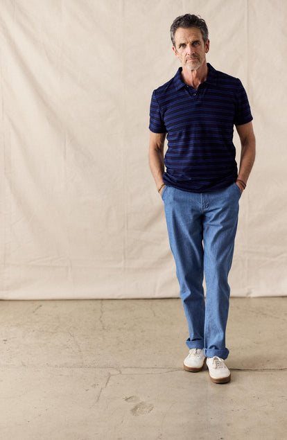 fit model walking wearing The Organic Cotton Polo in Rinsed Indigo Stripe