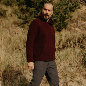 fit model walking in a field in The Nomad Hoodie in Burgundy Sherpa