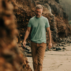 fit model walking along the Rocky Coast in The Cotton Hemp Tee in Teal