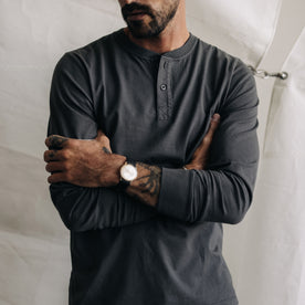 fit model with his arms folded wearing The Organic Cotton Henley in Faded Black