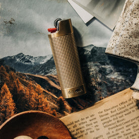 editorial image of The Lighter Sleeve in Brass on top of magazines